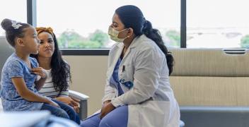 A female doctor engaging with two children in the hospital